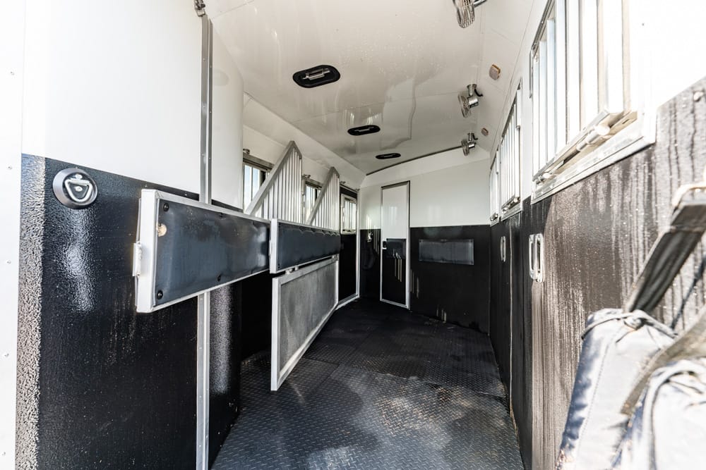 Interior of a horse trailer with side stalls and rubber flooring, ready for loading horses
