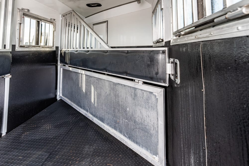 Interior of a horse trailer with metal dividers and a rubber-textured floor