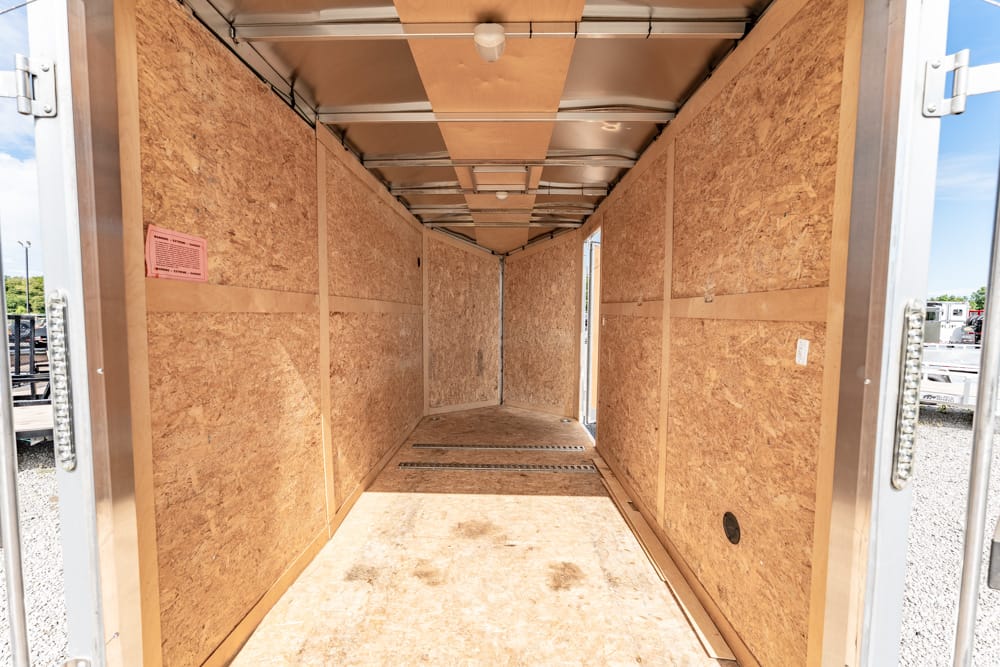 Interior of an empty plywood cargo trailer, long narrow space with bare walls and overhead lighting at the top.