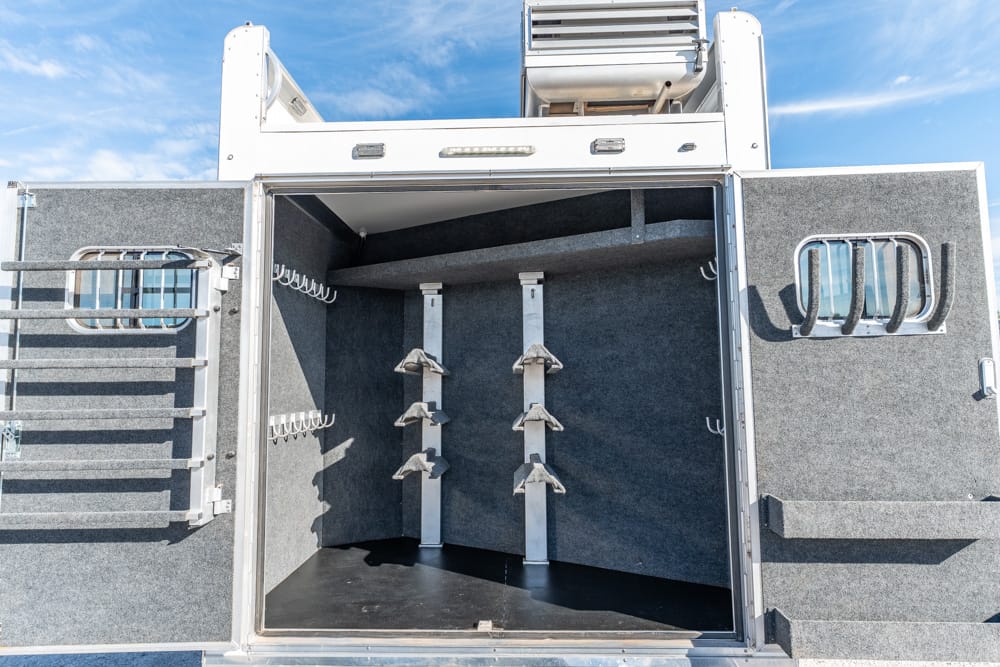 Open cargo bay of a gray utility trailer showing wall-mounted racks, hooks, and padding inside.