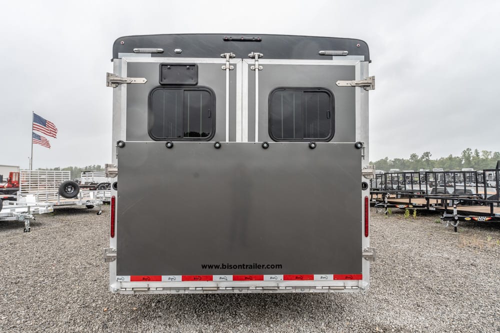 Rear view of a silver horse trailer with two square windows and a closed back door; www.bisontrailer.com printed along the lower edge.