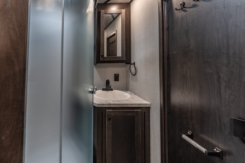 Small bathroom with dark wood cabinet, marble countertop, oval sink, and framed mirror.