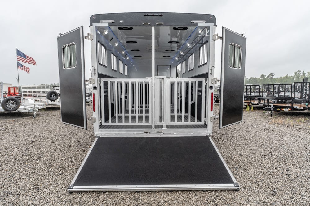 Back of a silver horse trailer with double doors open, lowered ramp, and empty stalls inside.