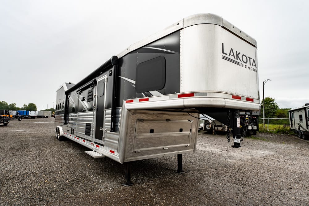 A Lakota Big Horn fifth-wheel luxury trailer parked on a gravel lot, showing the front hitch and stabilizing jacks.