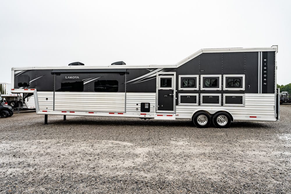 Long two-tone Lakota horse trailer with multiple stalls and windows parked on a gravel lot.
