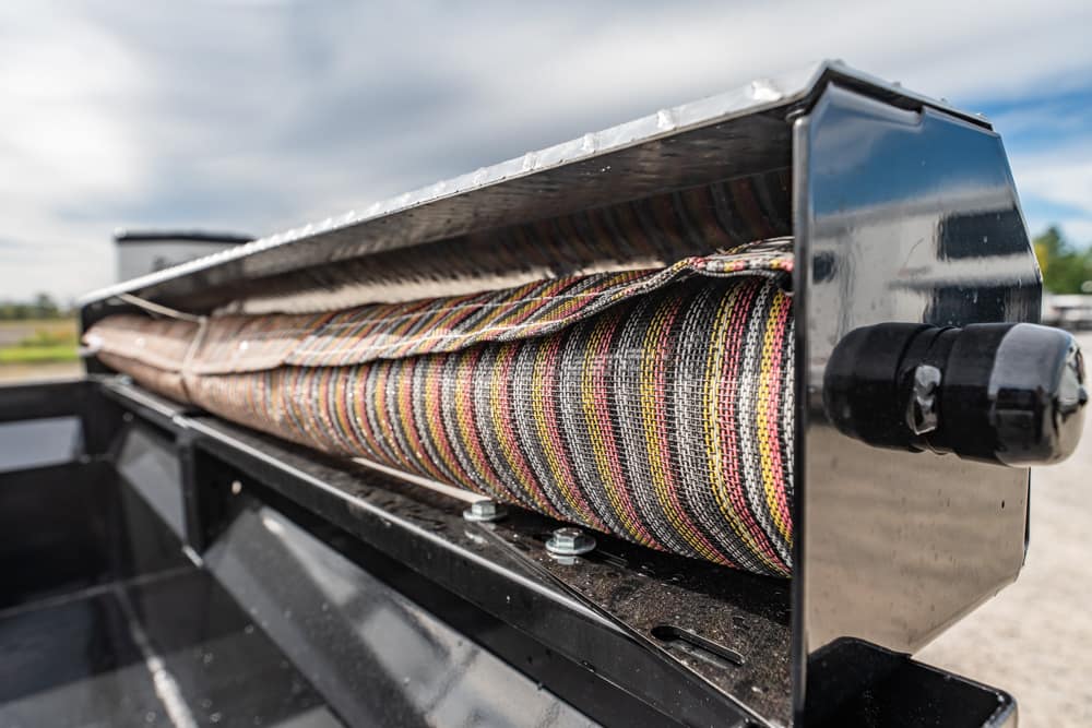 Close-up of a metal winch drum with colorful braided rope wound around it on a trailer bed