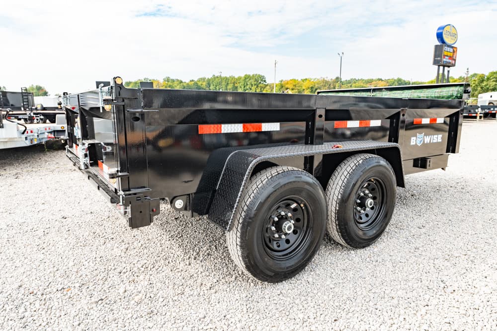 Black dual-axle dump trailer on a gravel lot, with red/white reflective stripes and the Wise logo visible on the side.