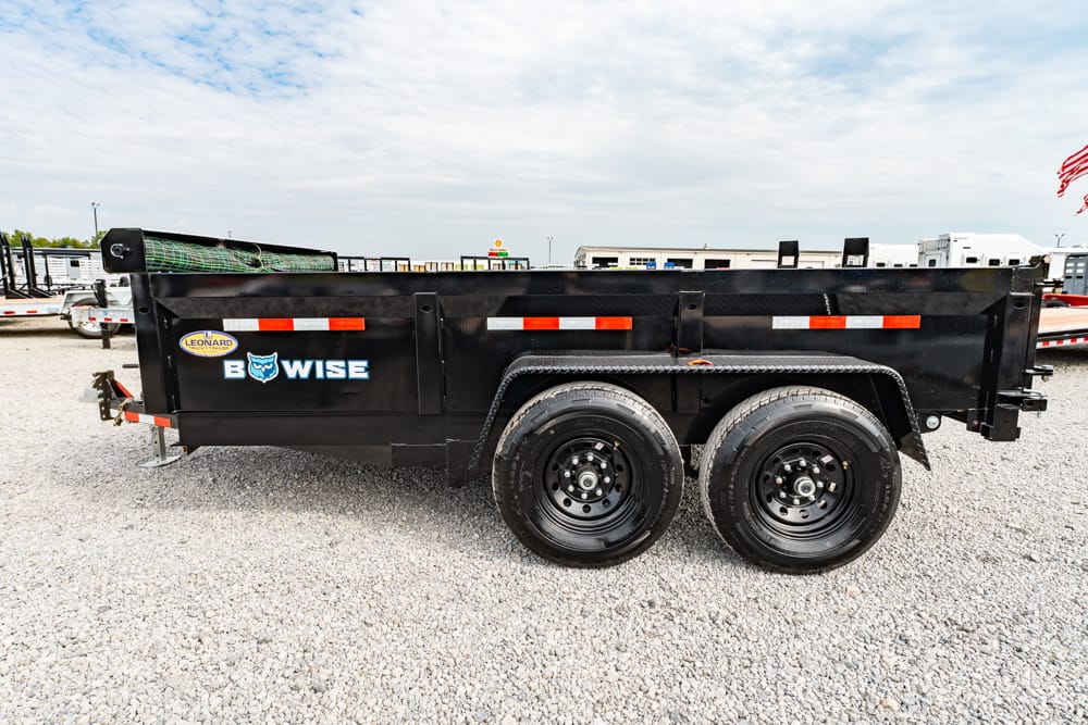 Black dual-axle dump trailer on a gravel lot, with orange/white safety stripes and Bow Wise logo on the side.