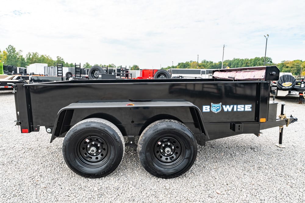 Black dual-axle dump trailer with BowWise branding on a gravel lot.