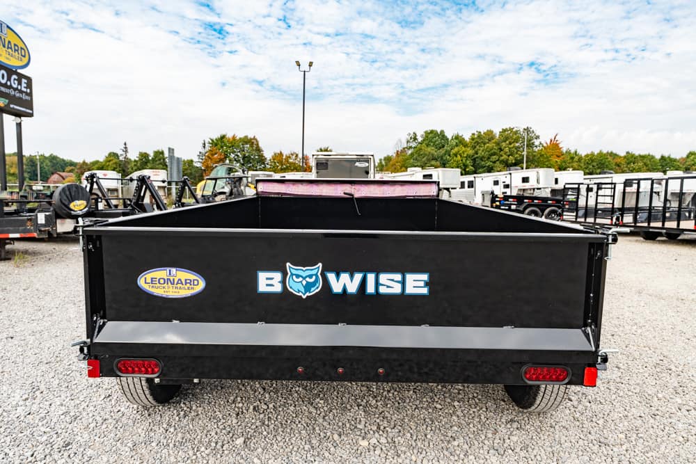 Black dump trailer with 'BOWISE' logo and Leonard trailer logo parked on a gravel lot, back view showing tail lights and rails