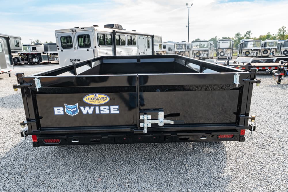 Black dump trailer with BowWise and Leonard logos parked on a gravel lot among other trailers.