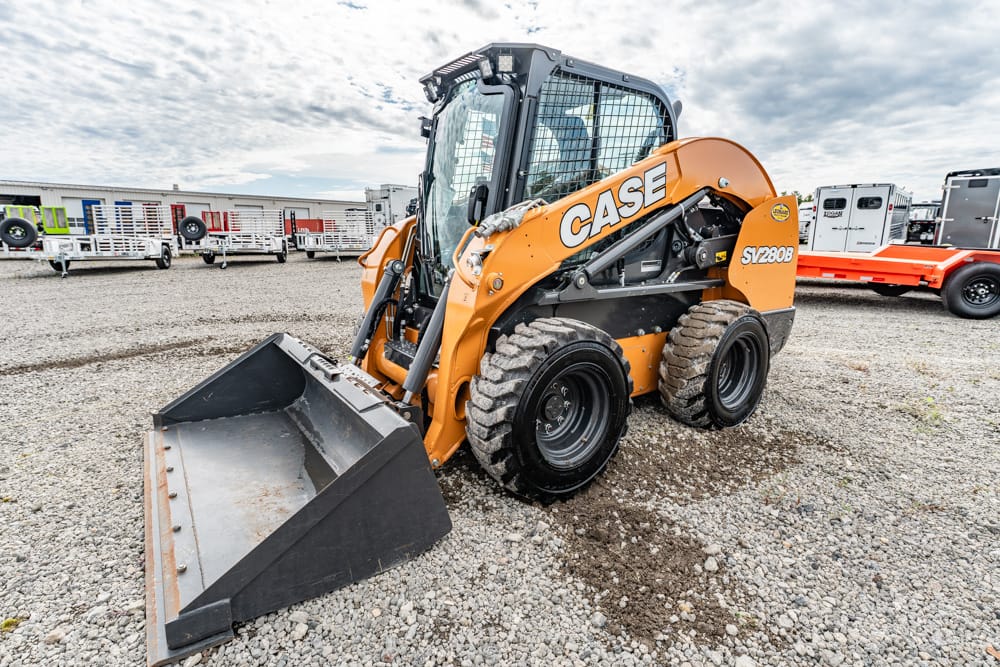 Orange CASE skid-steer loader with front bucket on a gravel lot used for construction gear storage