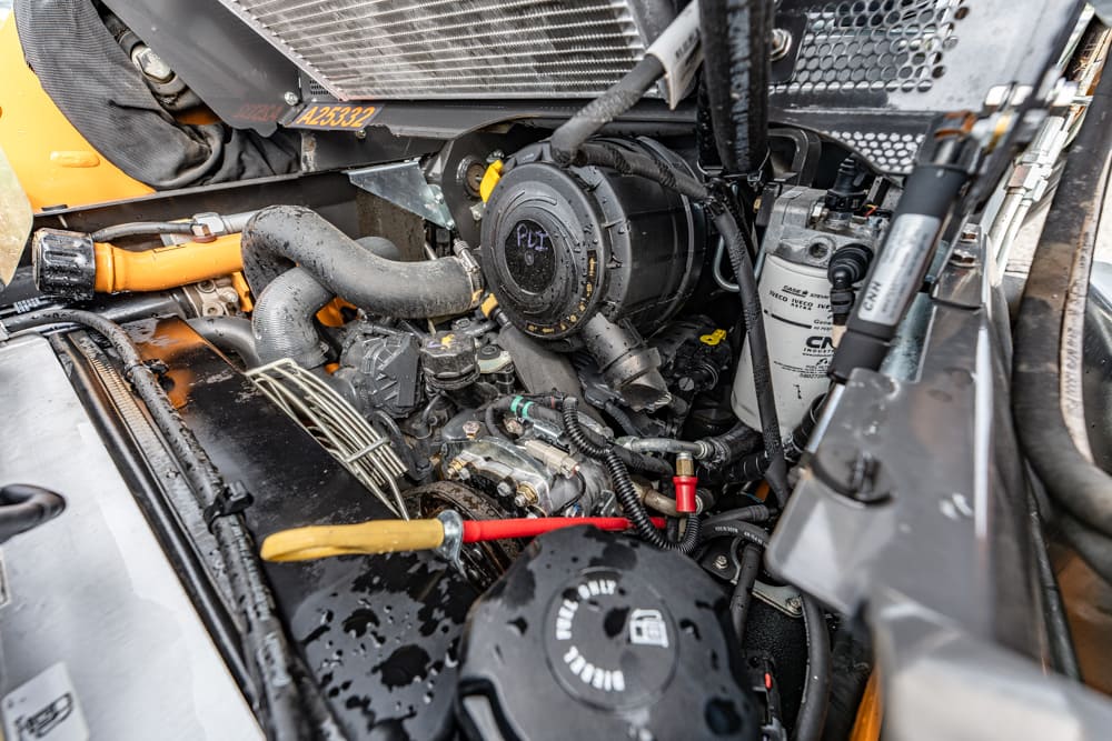 Close-up of a truck engine bay with hoses, belts, and a coolant reservoir in view