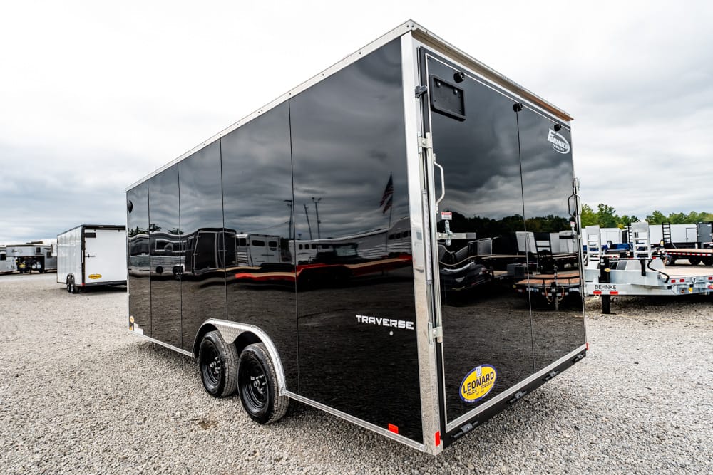 Black enclosed dual-axle trailer in a gravel lot, reflecting surrounding trailers on glossy sides.