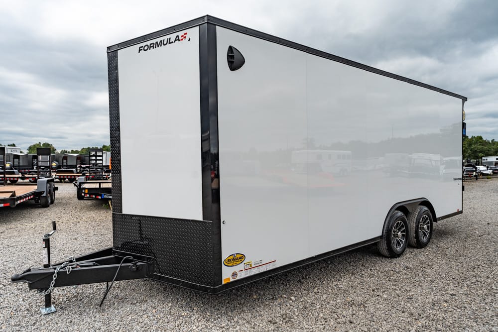 White two‑axle enclosed trailer on a gravel lot, with a black diamond‑plate front and FORMULA branding near the top corner at the front.