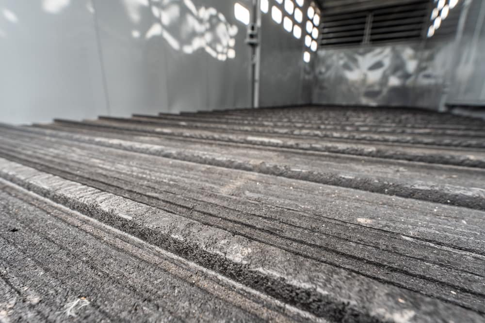 Close-up of a weathered ribbed roof panel with grooves and dust inside a metal shed.