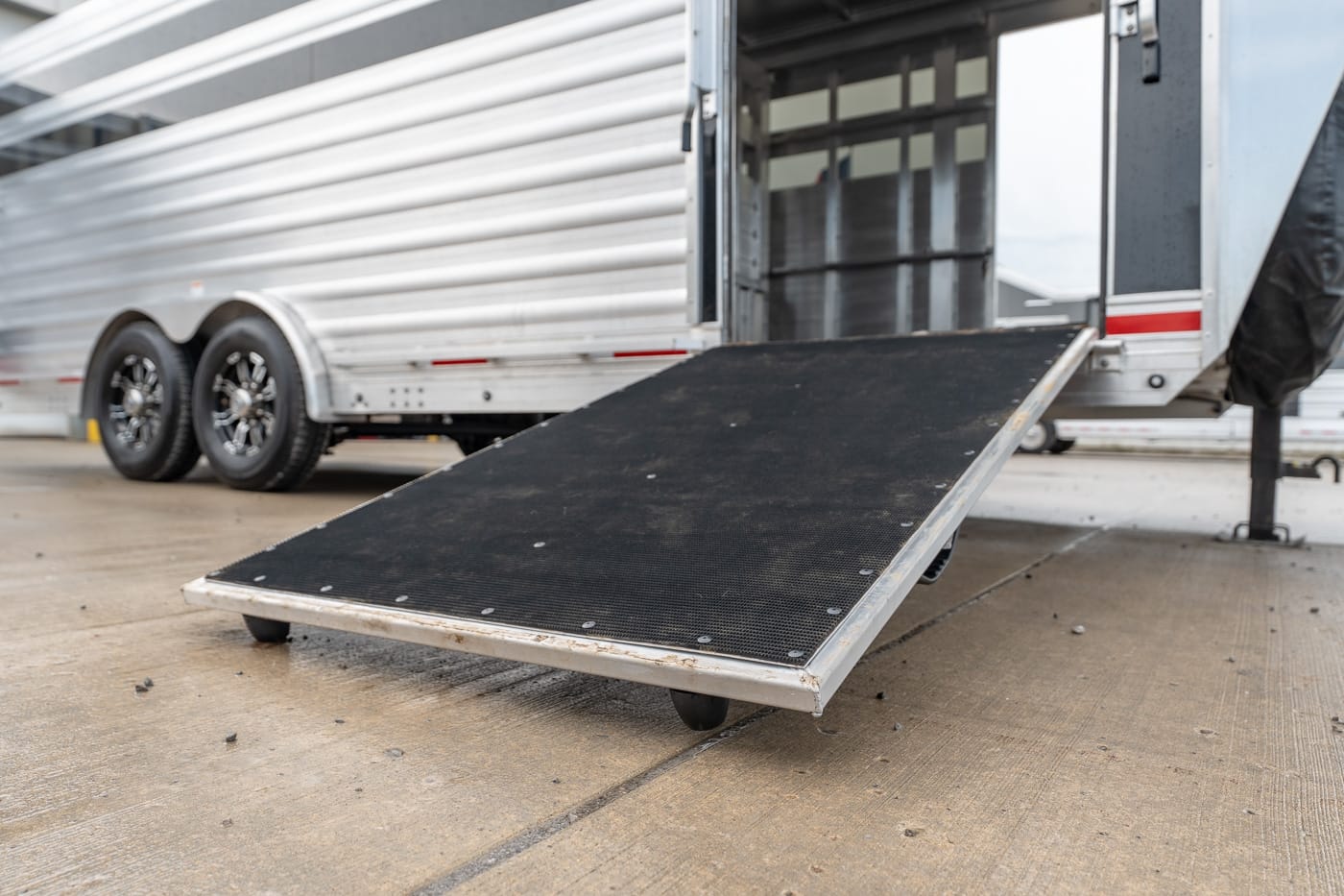 Trailer with a lowered black loading ramp for unloading cargo.