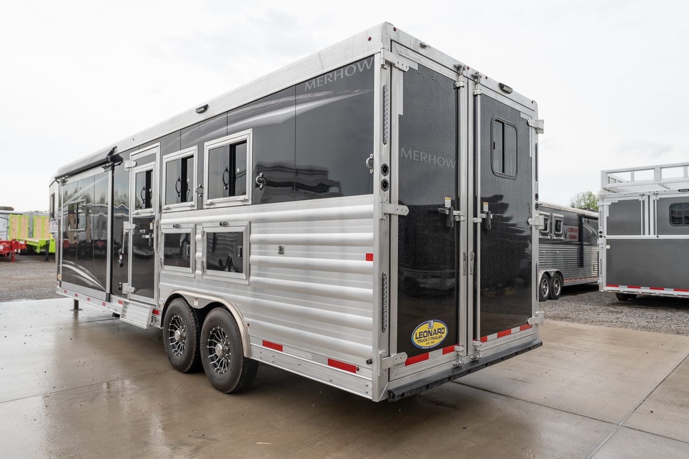 Enclosed, dual-axle horse trailer in black and silver with side windows and rear double doors.
