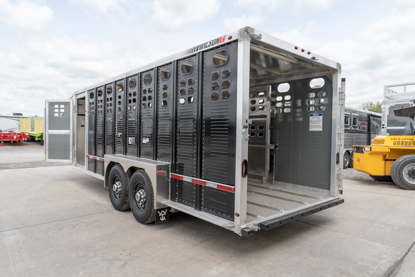 Grey livestock trailer with open rear ramp and ventilated sides, ready for loading animals.