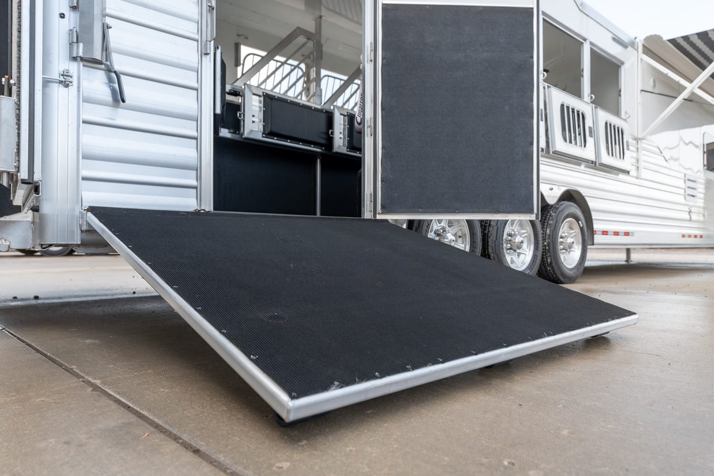 Loading ramp extended from a silver horse trailer, ready for boarding horses or equipment.