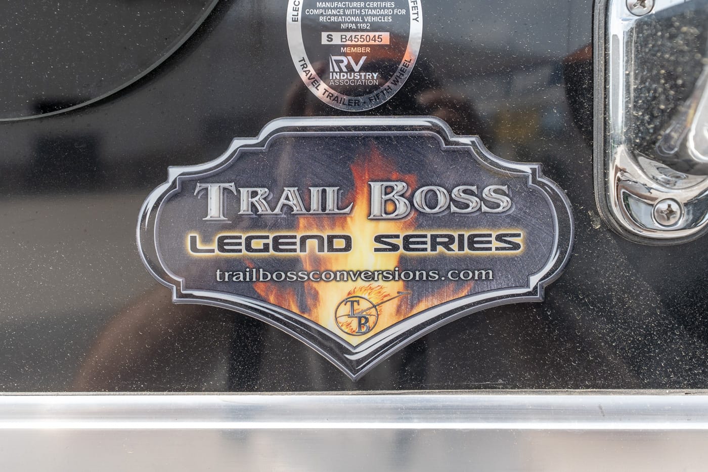 Badge on a black surface reading 'Trail Boss Legend Series' with a flame motif and the URL trailbossconversions.com.
