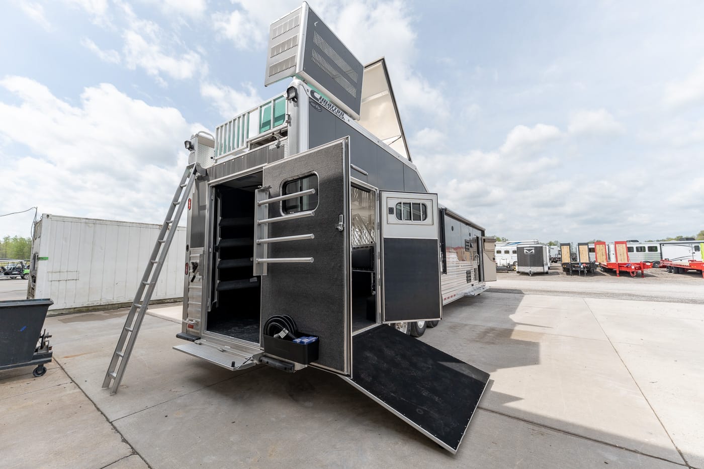 Mobile event trailer with open rear doors, exterior stairs, and a down-angled ramp for loading equipment.