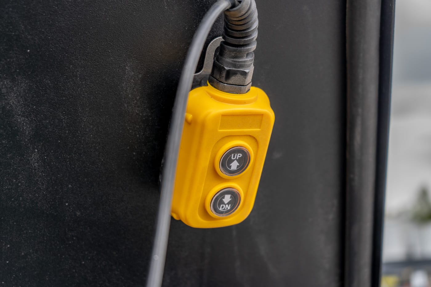 Close-up of a yellow dual-button control on a black panel, with UP and DOWN arrows on circular buttons.
