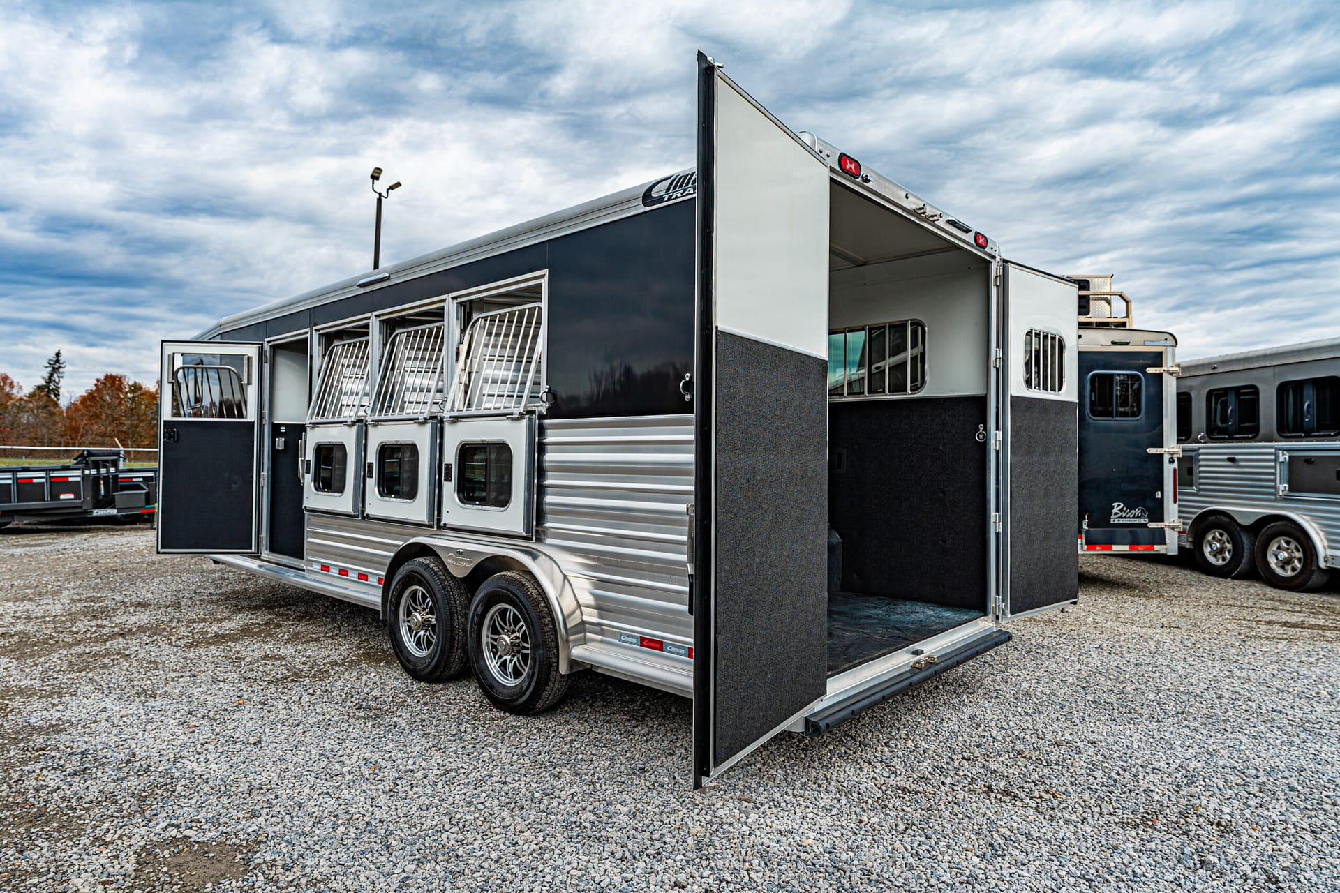 Silver aluminum horse trailer with the rear ramp down and visible stall doors on the side portions