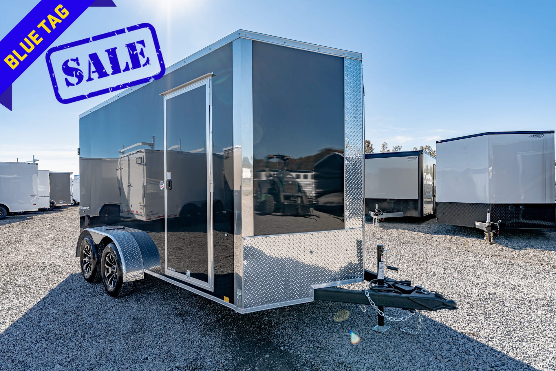 Trailer on a gravel lot with a blue 'SALE' stamp and blue 'BLUE TAG' banner in the top-left corner, indicating a sale.