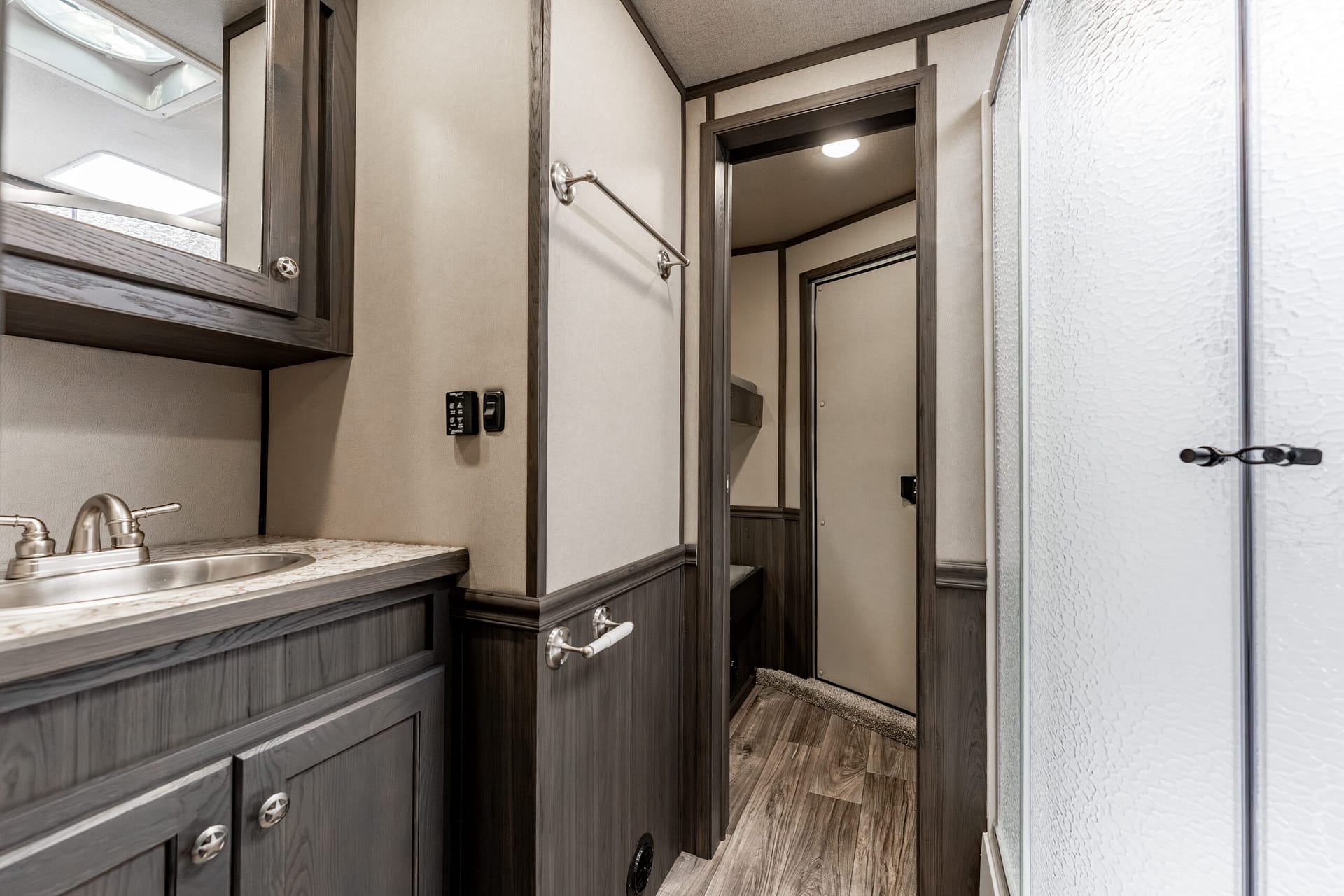 RV bathroom vanity with dark wood cabinetry, granite-like countertop, and brushed-silver faucets.