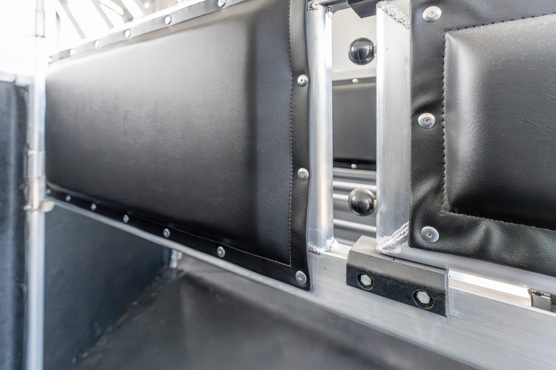 Close-up of black padded panels and silver metal framework with rivets in an industrial cabinet interior.