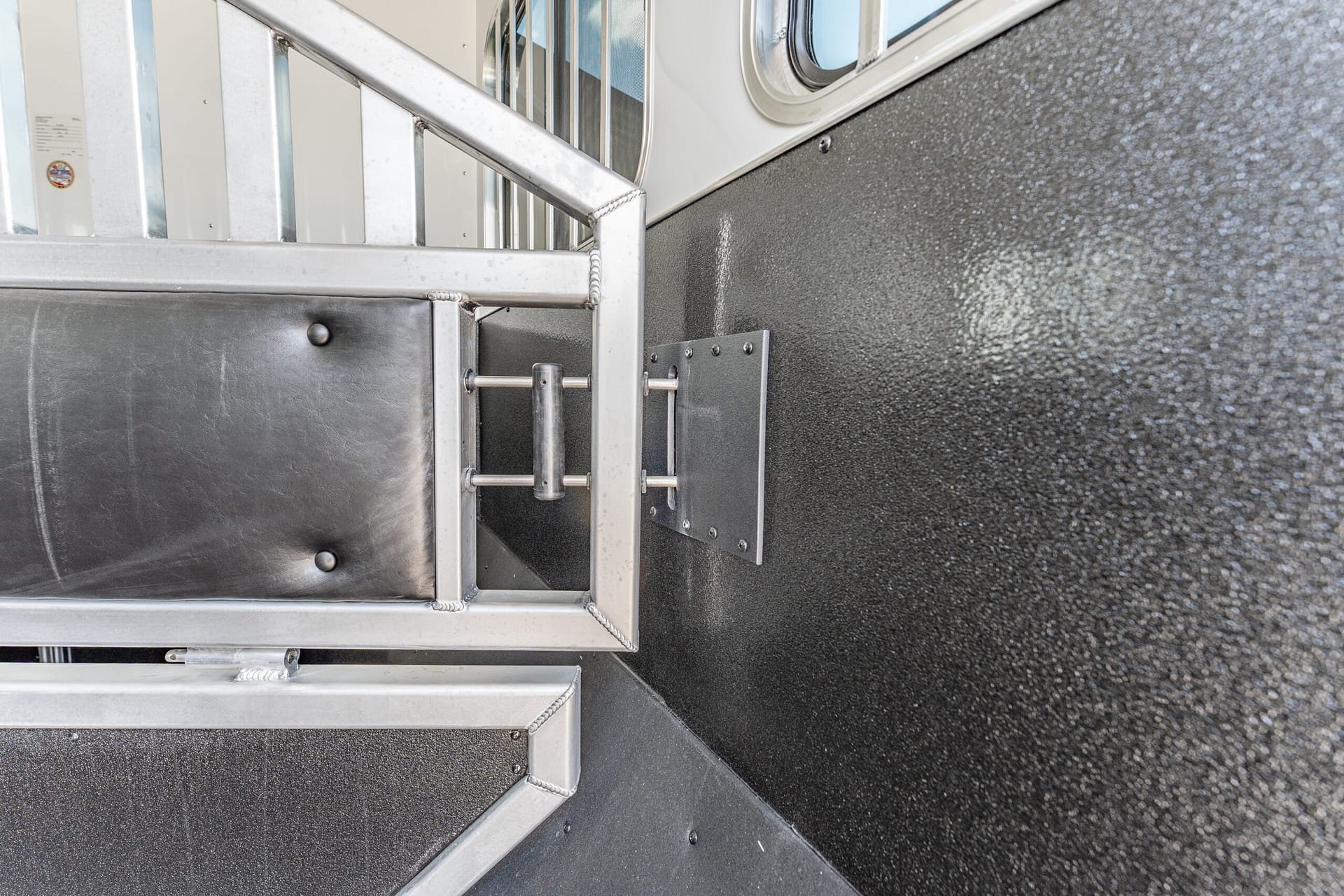 Close-up of metal staircase with welded joints and railing against a textured gray wall.
