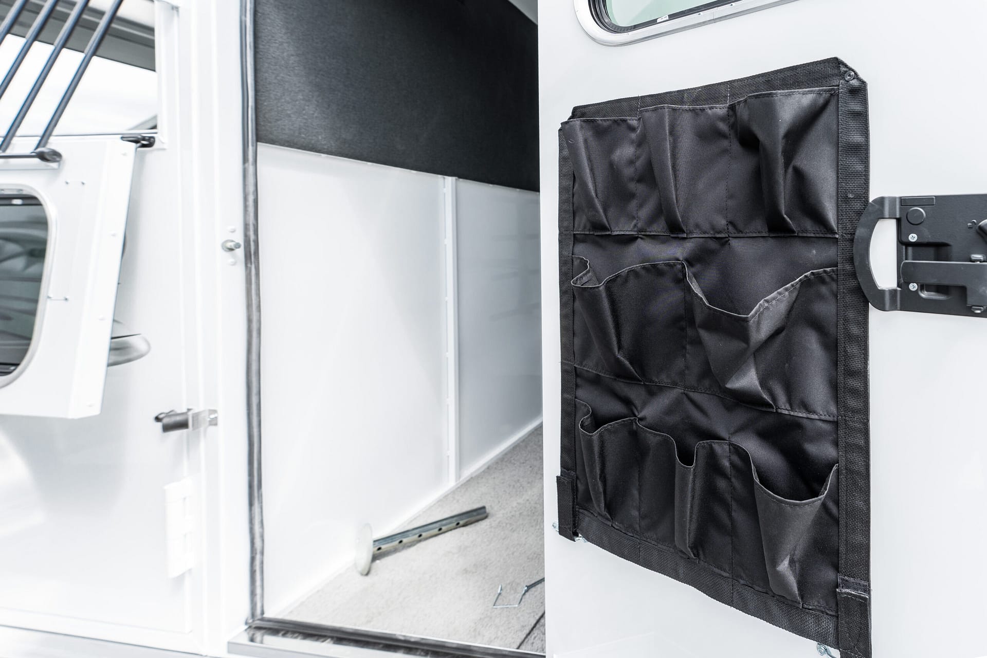 Open vehicle doorway showing a black fabric tool organizer with multiple pockets hanging on the door interior.