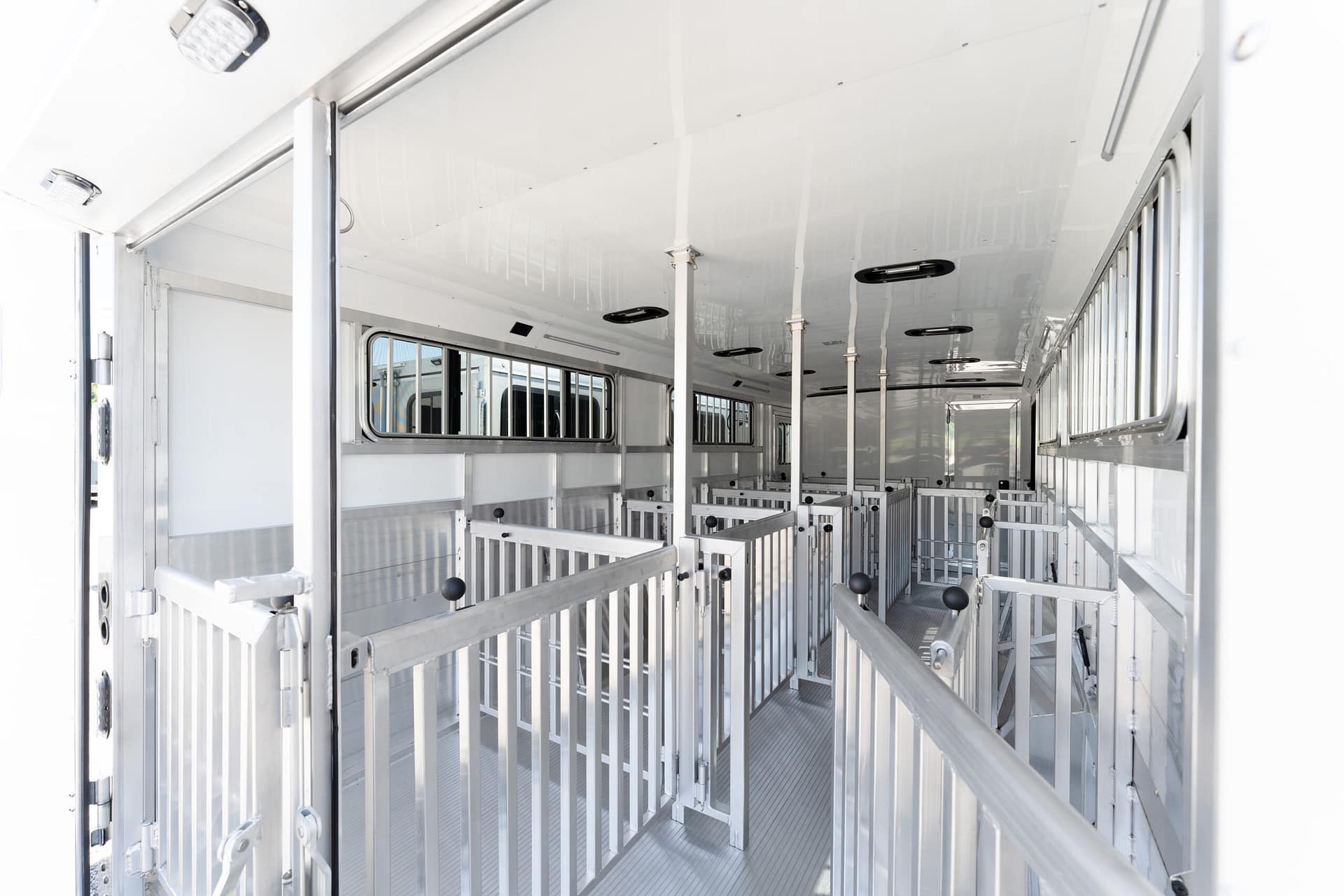 Interior of a metal horse trailer with multiple stalls and metal gates, empty and ready for loading horses
