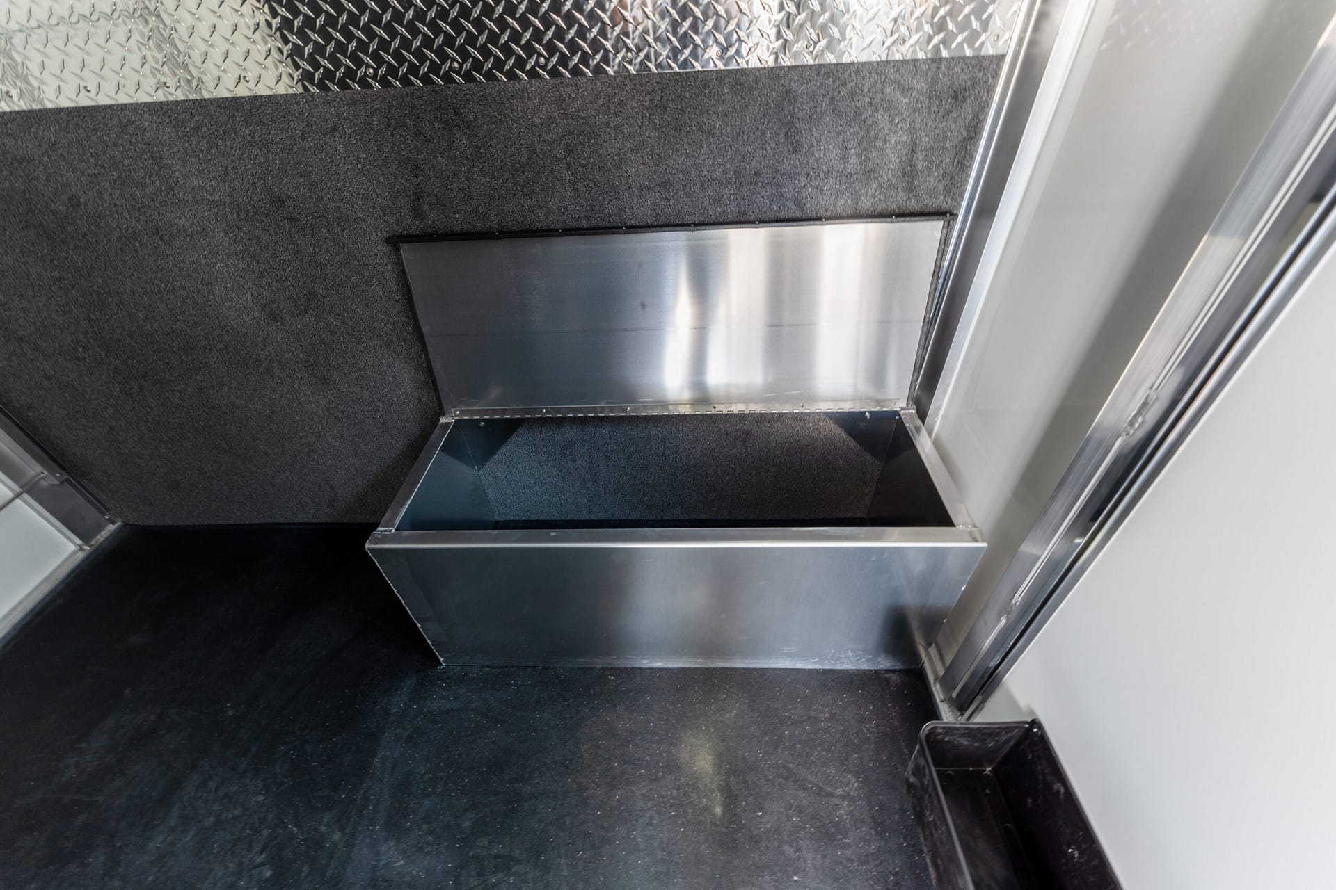 Interior of an industrial metal stairwell with diamond-plate walls and stainless steel steps surface.