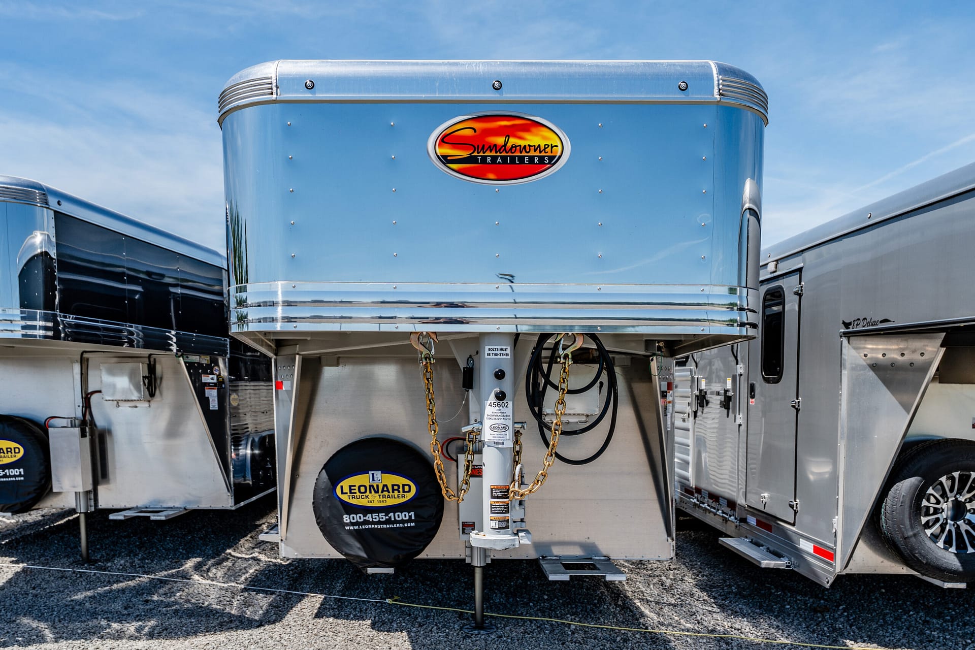 Blue polished trailer nose with Sundowner Trailers logo and safety chains hanging from the hitch area.