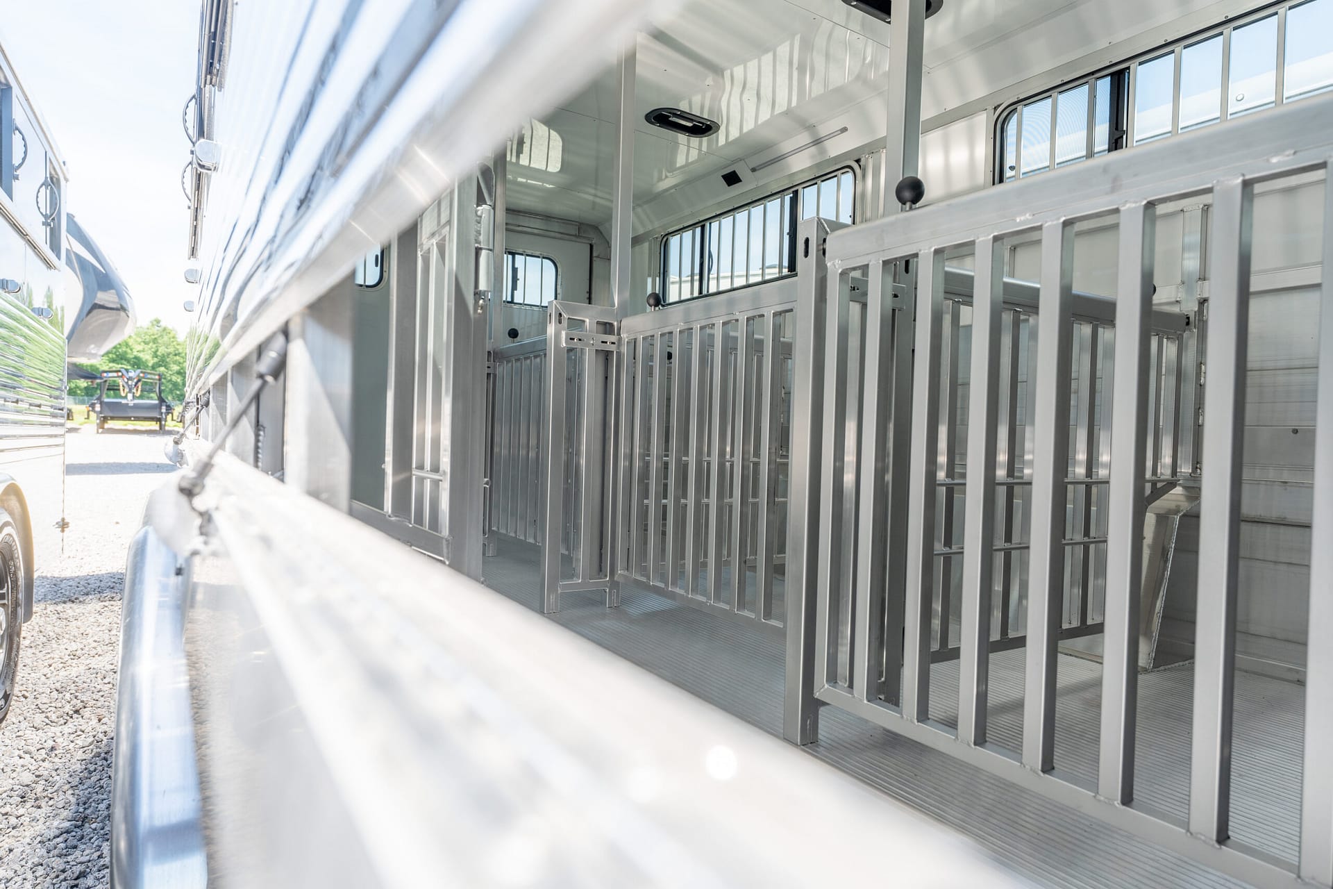 Interior of a silver horse trailer with individual metal stalls and dividers