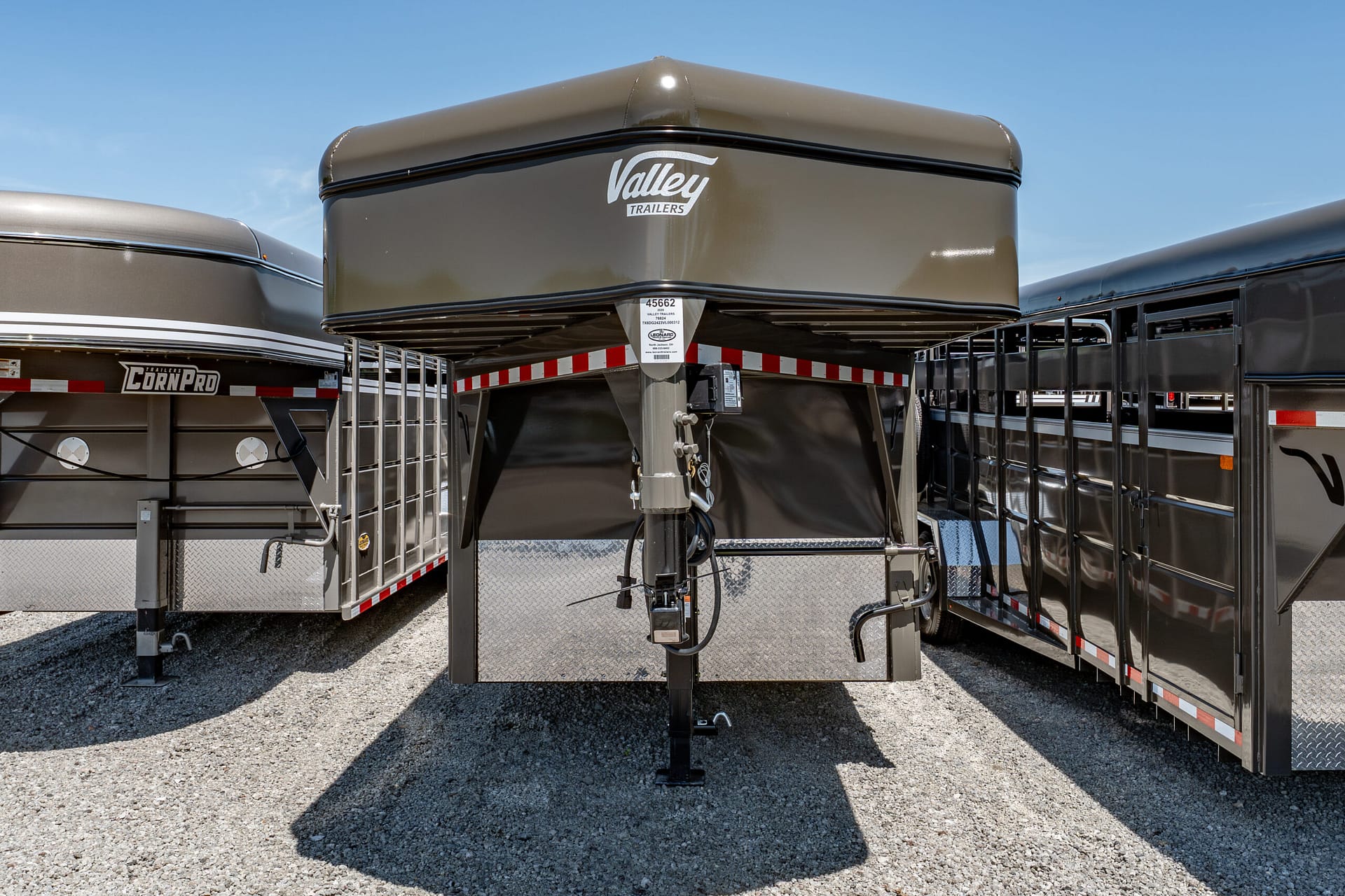 Gray Valley Trailers gooseneck trailer raised on its hitch, parked among other trailers on a gravel lot.