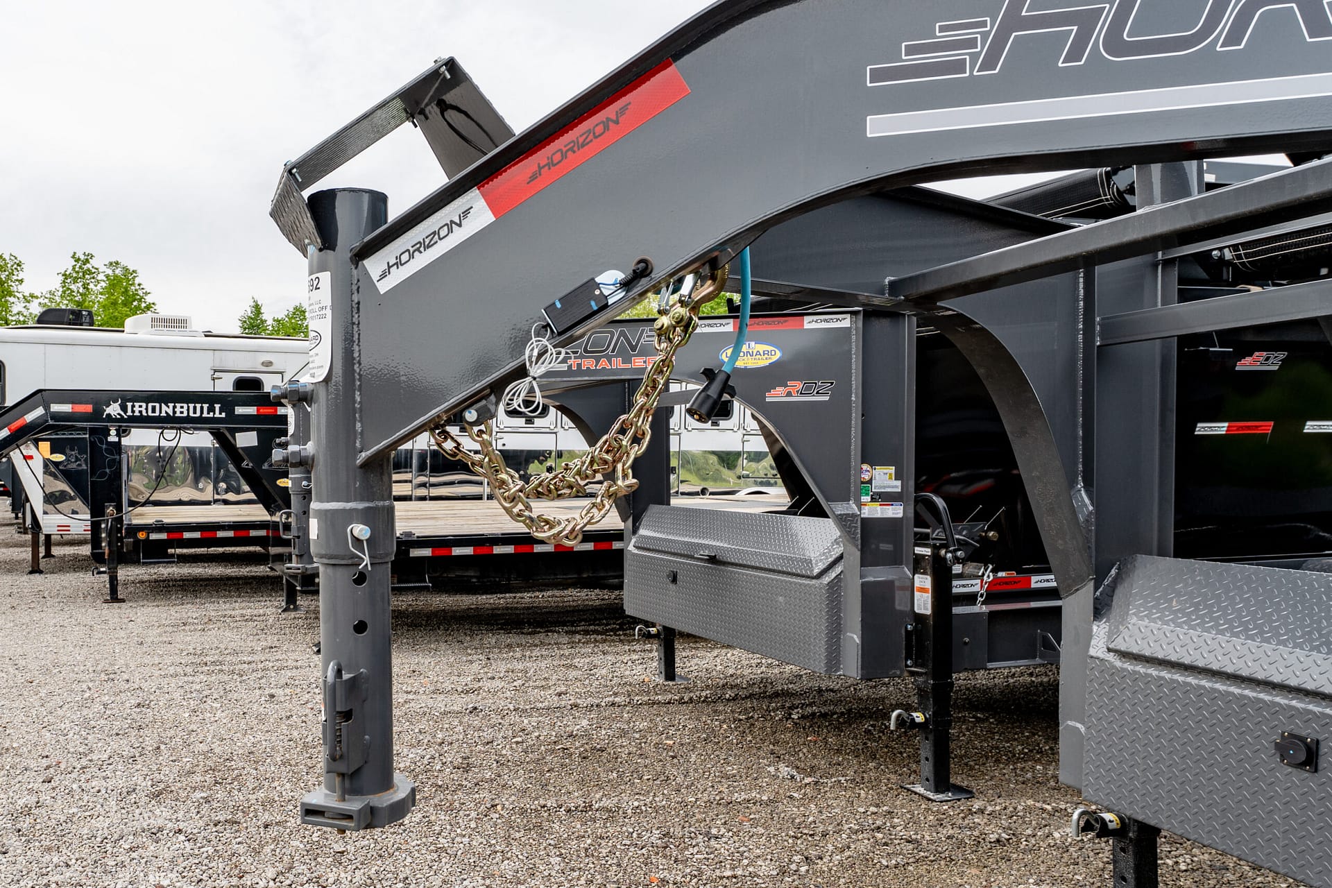 Close-up of a gray Horizon trailer frame with chains and metal beams in a gravel lot.