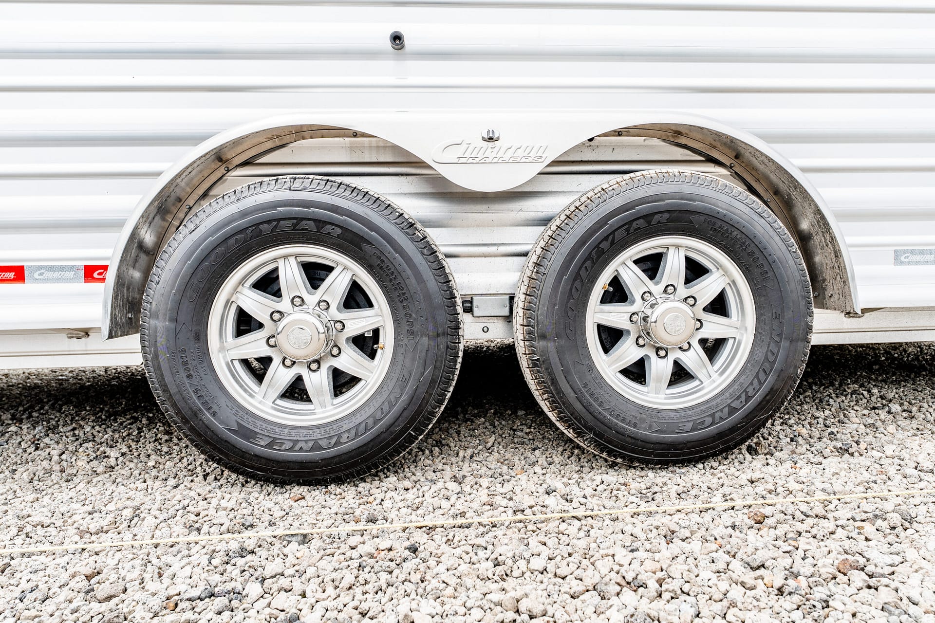Close-up of two trailer wheels with gray Goodyear tires and a white fender on a metal trailer.