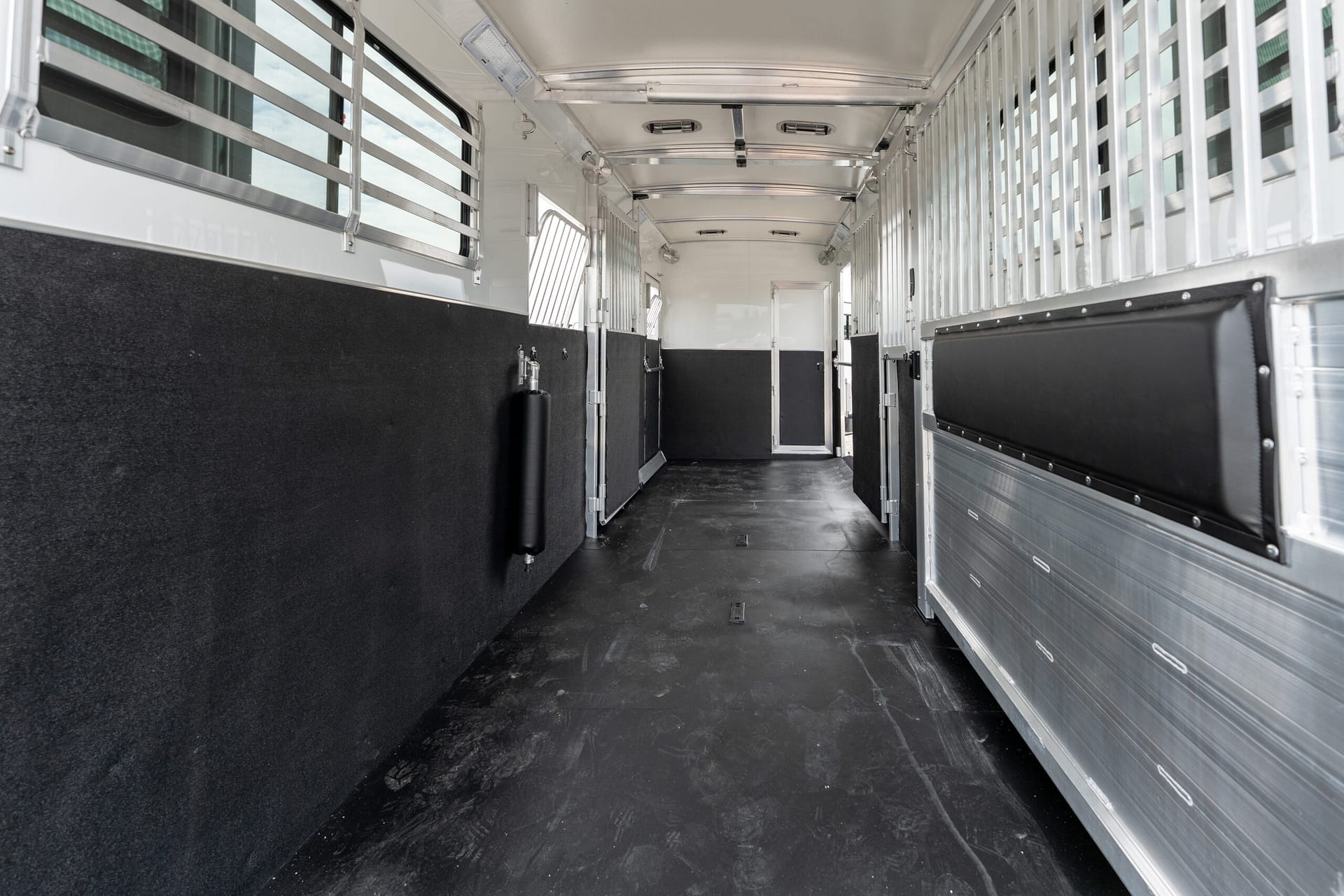 Interior of a clean horse trailer with stalls along both sides and a central aisle