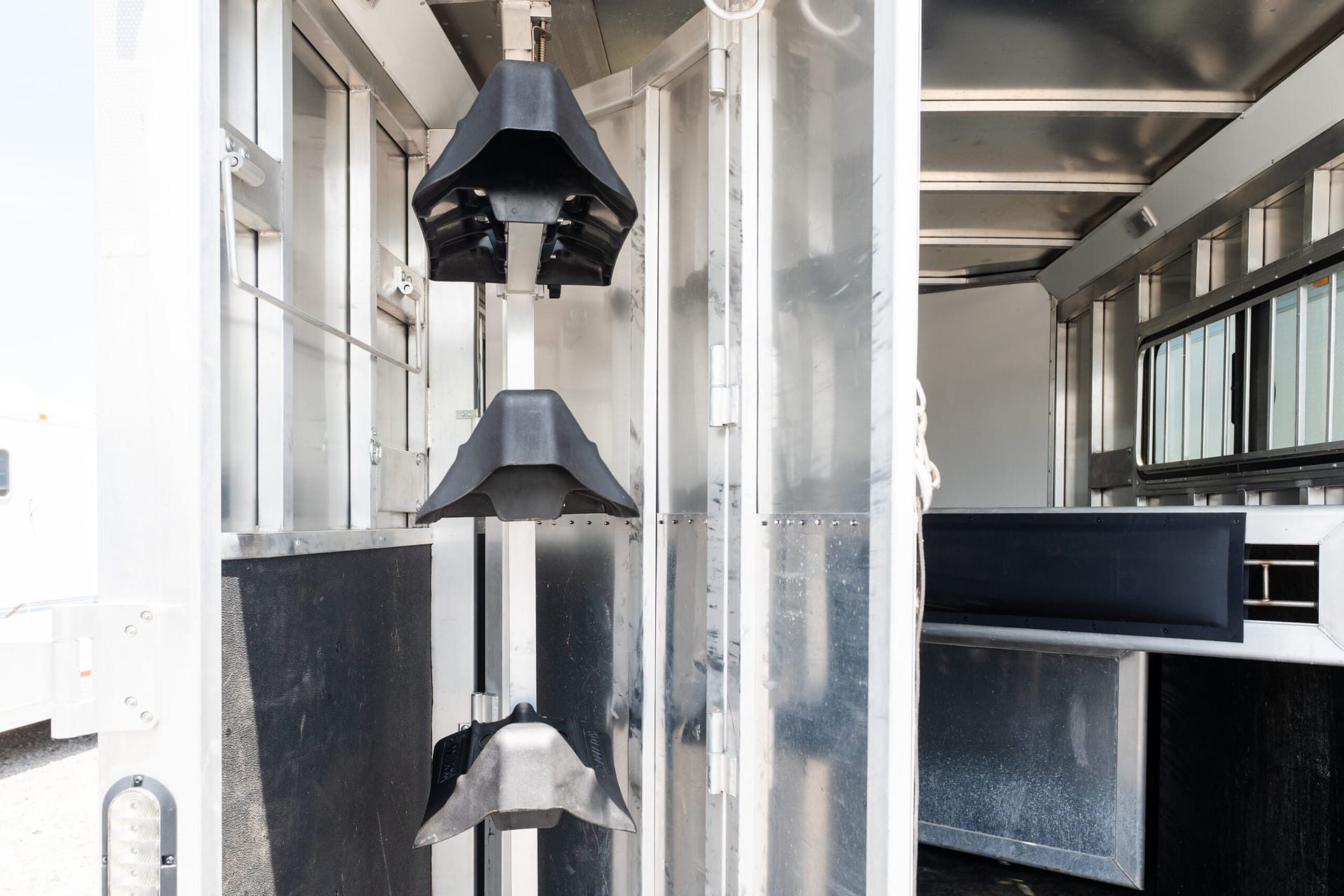 Interior of a metallic trailer with vertical rails and black rubber wheel guards hanging along a central beam for protection or support.” (informative)