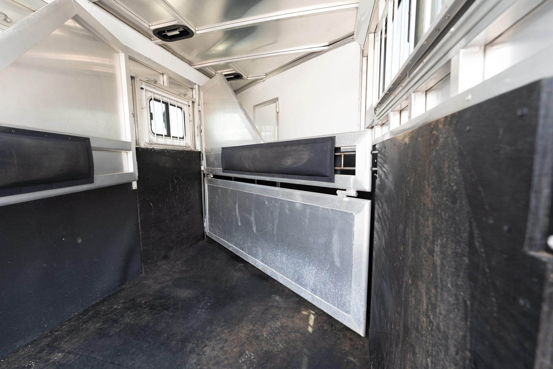 Interior of an empty aluminum cargo trailer with black side panels and rails along the walls.