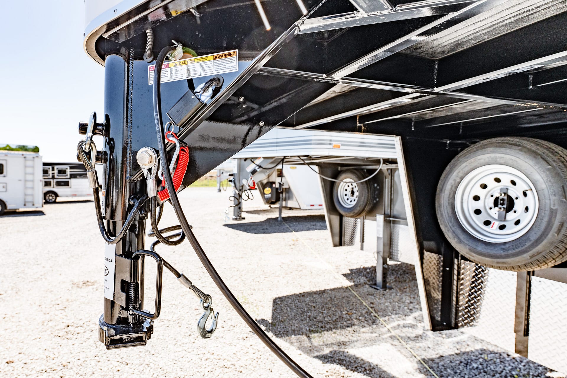 Close-up of a trailer hitch jack and tangled electrical cables under a black trailer frame, with a wheel visible in the background.