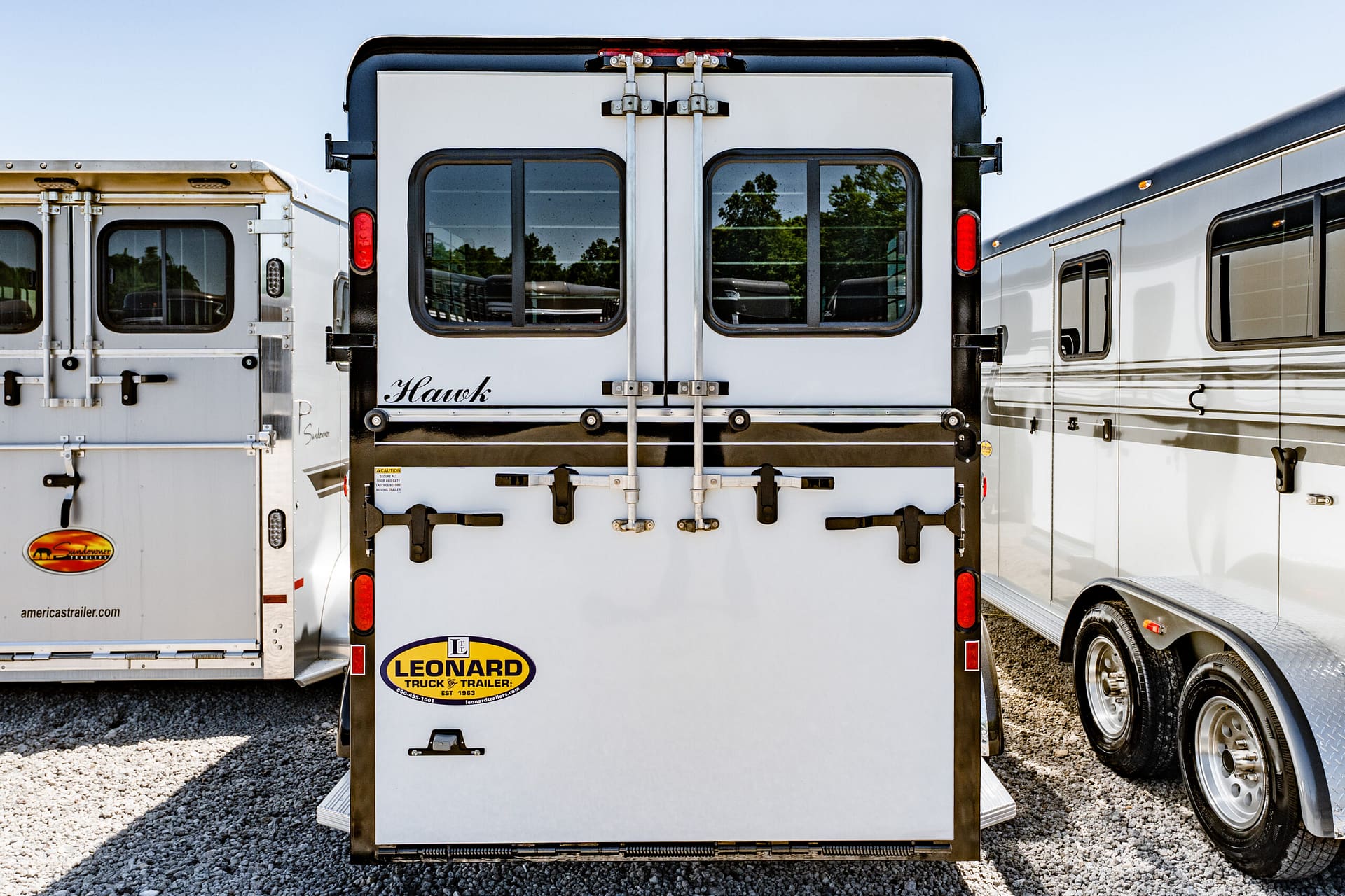 Rear view of two silver freight trailers with closed double doors and red taillights, Leonard Truck & Trailer logo visible on the back door.