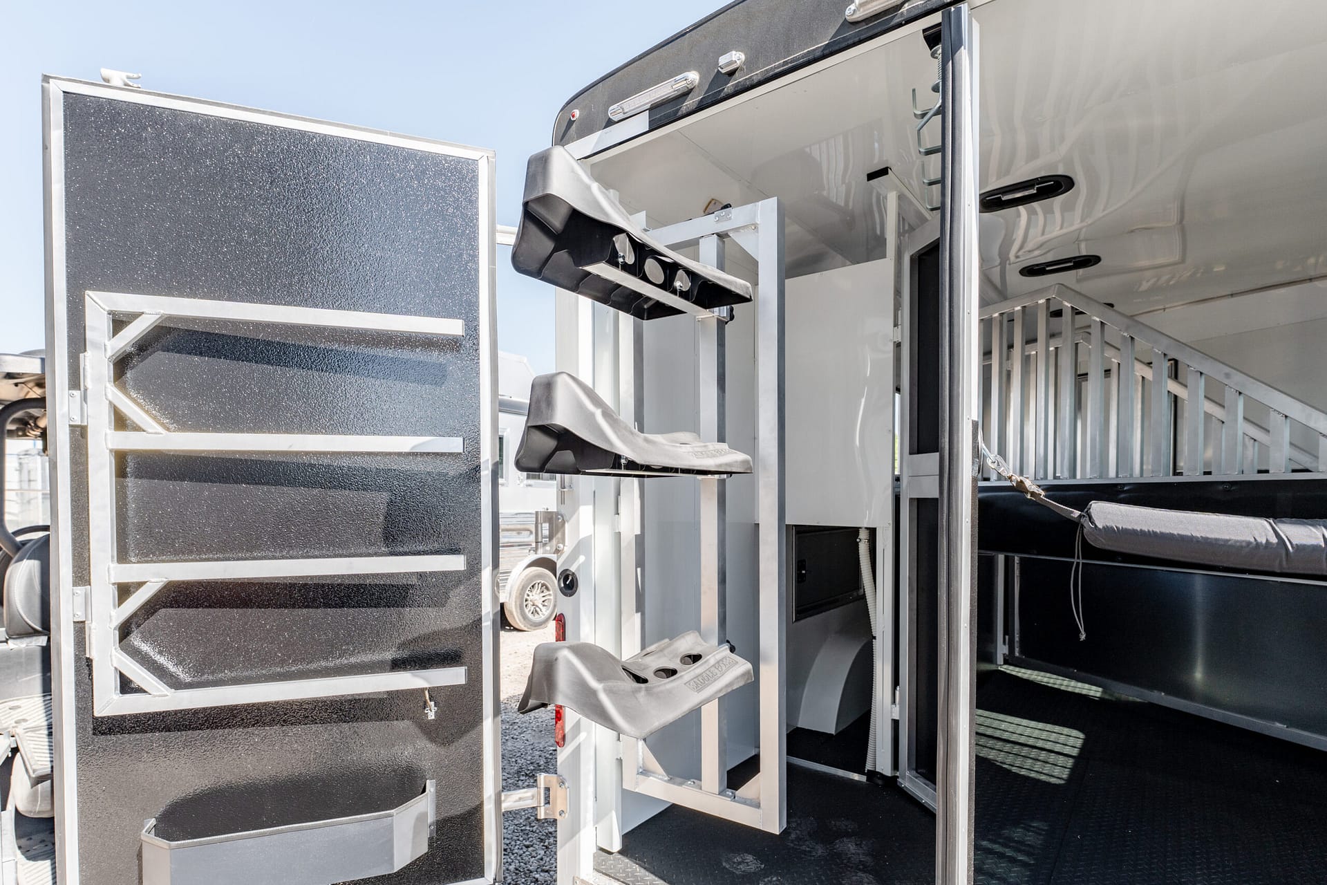 Interior of a metal trailer with fold-out aluminum stairs and textured black panels for loading access