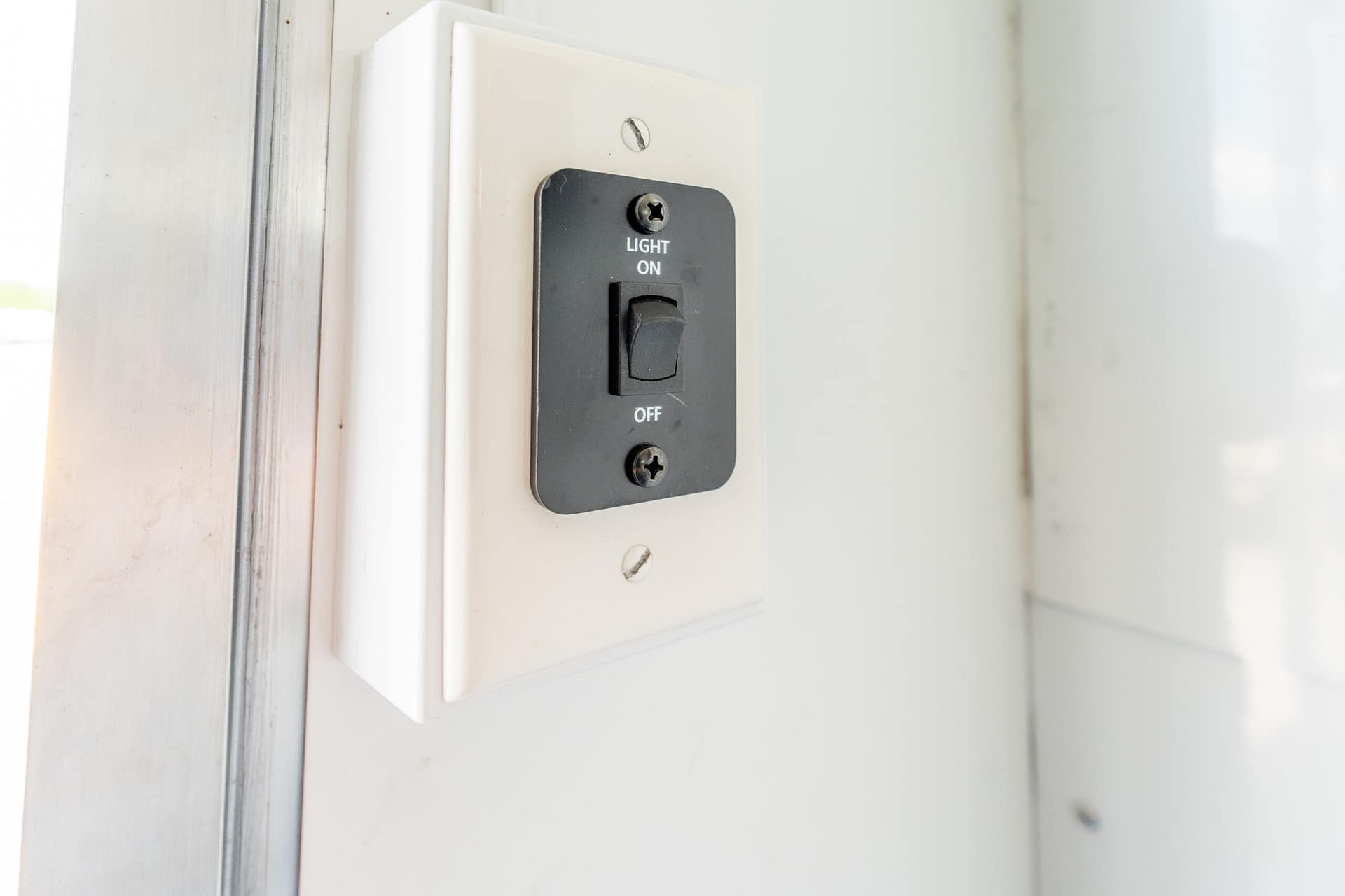 Close-up of a white wall plate with a black toggle switch labeled 'LIGHT ON' and 'OFF' above and below the switch.