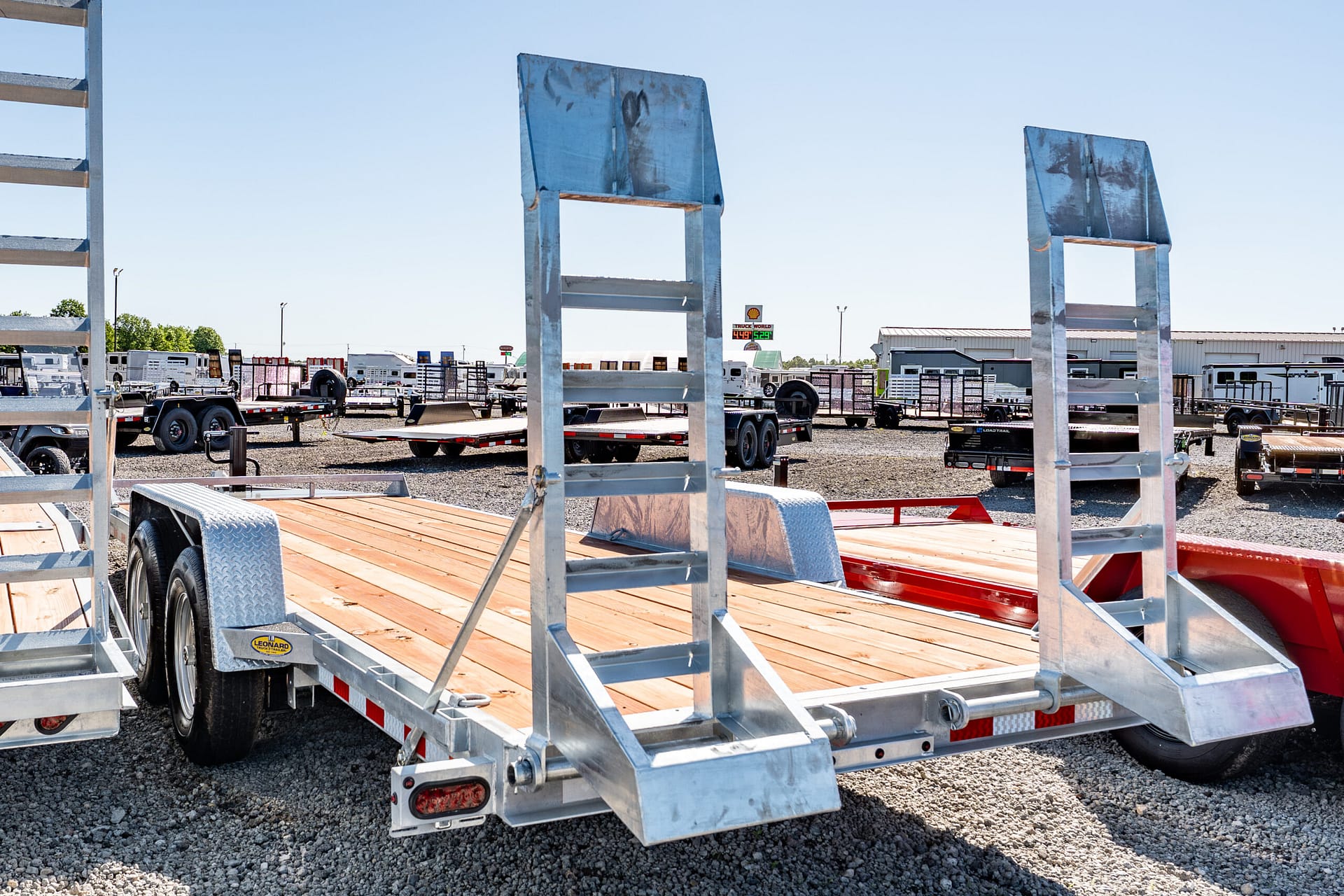 Metal-framed trailers parked in a gravel lot under a clear blue sky, an industrial yard scene.