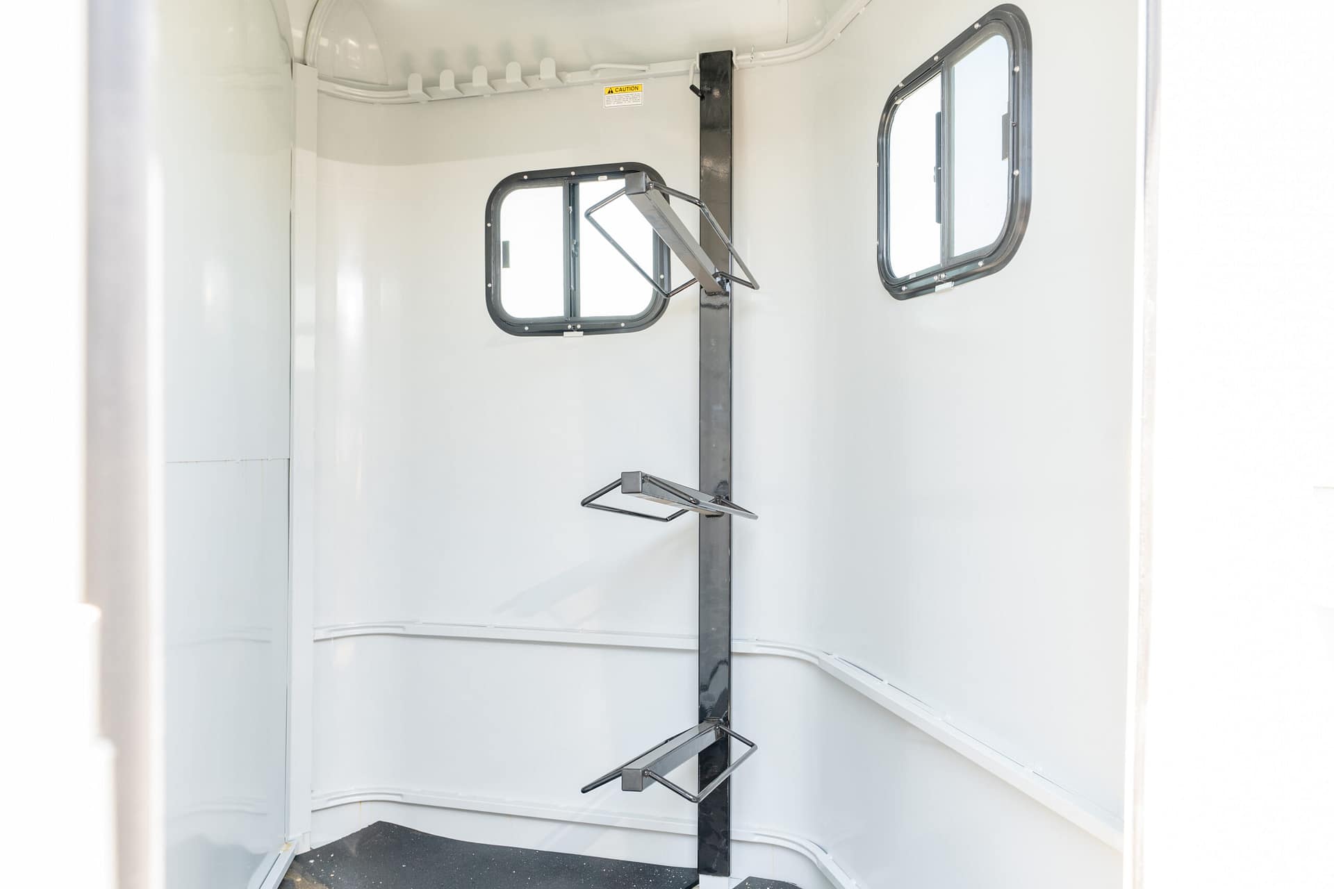 Interior of a white metal cabinet with two rounded rectangular windows and metal folding racks on the walls.
