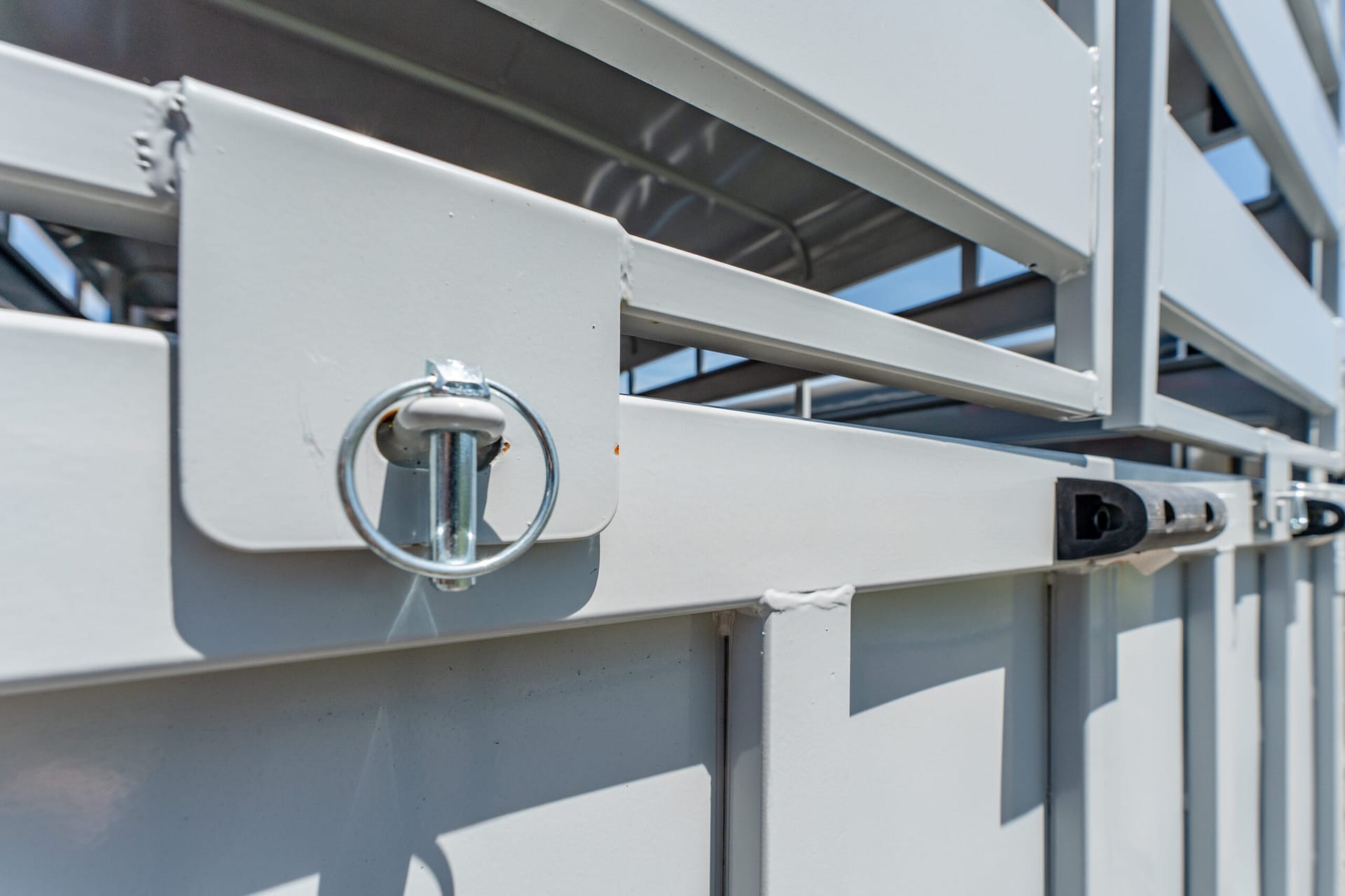 Close-up of a circular metal latch on a gray industrial container with stacked beams in the background